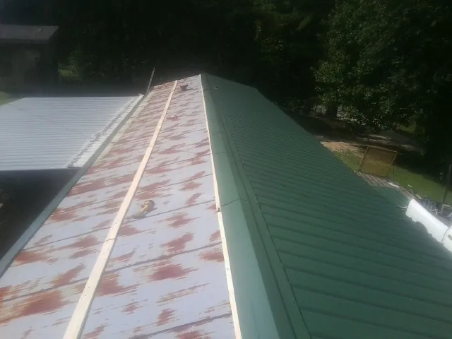 Old rusted panels beside newly installed green metal roofing — Wind Damage Roof Repair by Roofing Brothers in Plainville