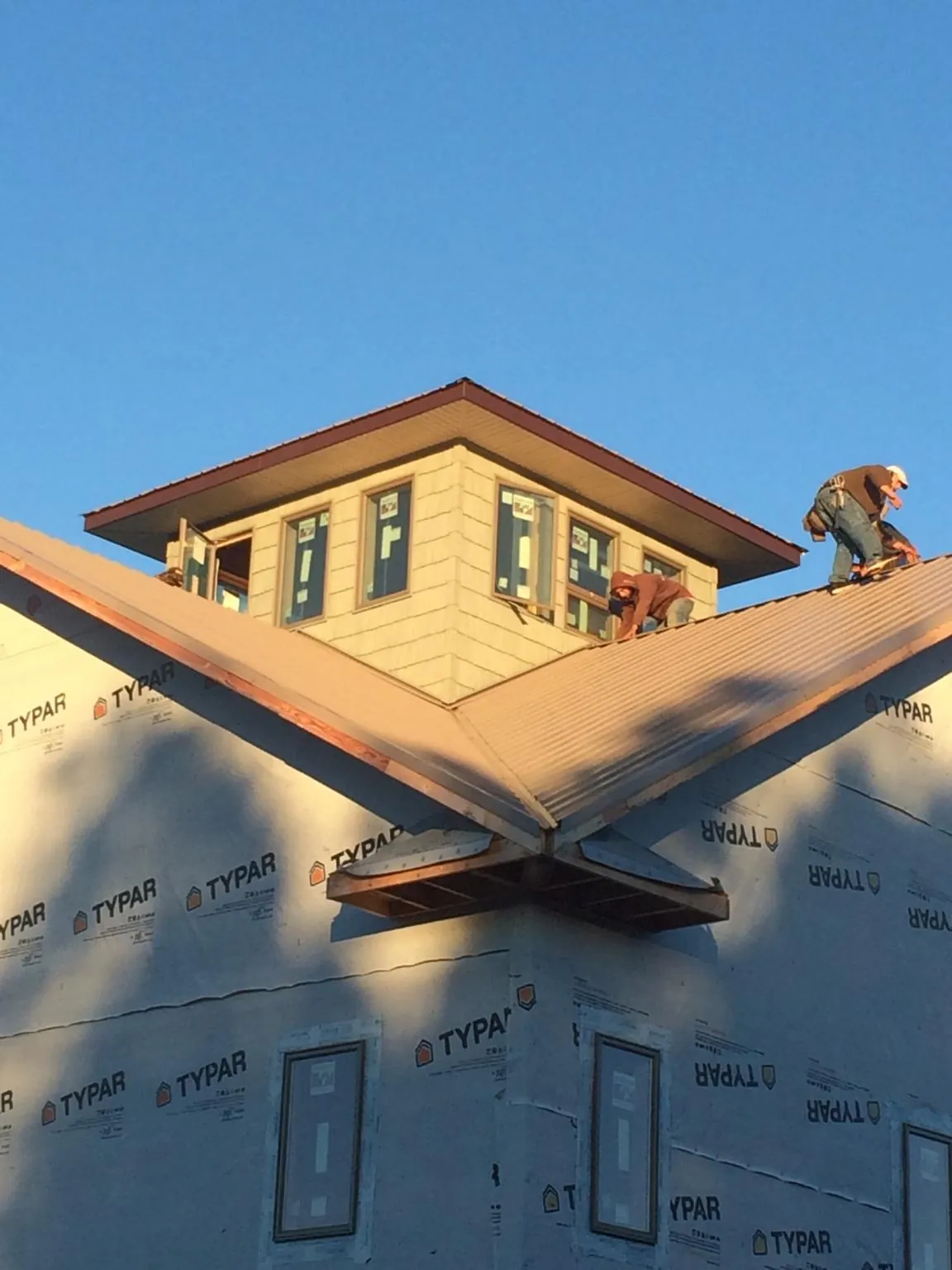 Roofers working around a rooftop cupola on a new metal roof at sunset — Roof Waterproofing in Plainville by Roofing Brothers